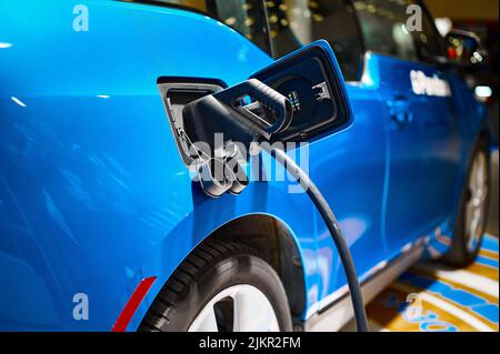 Charging electric automobile with plug at power station Stock Photo