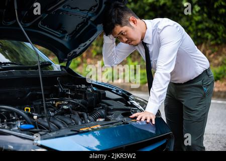Asian businessman car broken breakdown, young stressed man having trouble car failure problem looking in frustration at failed engine in the morning, Stock Photo