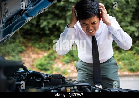 Asian businessman car broken breakdown, young stressed man having trouble car failure problem looking in frustration at failed engine in the morning, Stock Photo