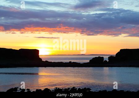 Sunset from Lunga in the Treshnish Isles of Scotland looking towards the Isle of Coll in the far distance Stock Photo