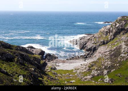 Rocky coastline and remote sandy bay on the Isle of Iona in the Inner Hebrides of Scotland Stock Photo