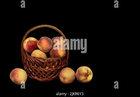 Image of a basket with a harvest of ripe peaches on a black background Stock Photo