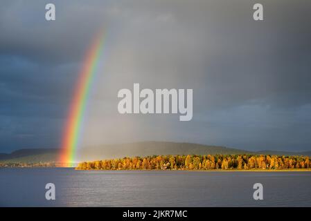 Rainbow over the autumn landscape, dramatic sky and light, forest trees in autumn colors. Lapland, Finland. Stock Photo