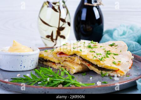 Fried pita bread with scrambled eggs, tomatoes, meat and cheese. Stuffed lavash Stock Photo