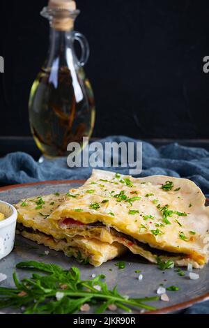 Fried pita bread with scrambled eggs, tomatoes, meat and cheese. Stuffed lavash Stock Photo