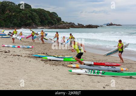 Male and female surf lifesavers training with their boards on Mount Maunganui beach, New Zealand Stock Photo