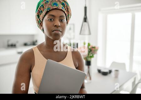Close up Portrait of a confident African woman with her arms crossed looking into the camera. Working from home and wearing a traditional headscarf Stock Photo