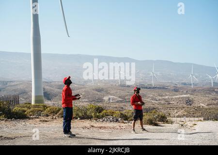 Multiracial engineer men using virtual reality headset on a windmill farm Stock Photo