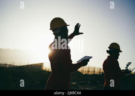 Engineers using futuristic virtual reality glasses while working on windmill farm with tablet - Renewable energy concept Stock Photo
