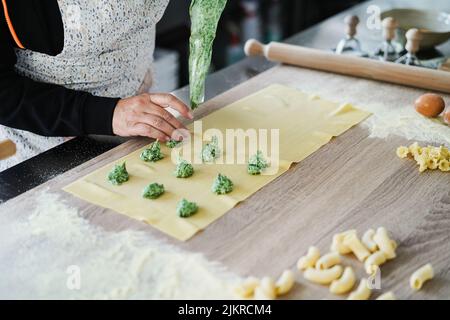 Woman prepare fresh made ravioli inside pasta factory Stock Photo