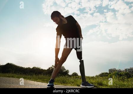 Young fit man with prosthetic leg doing stretching day routine outdoor - Focus on left hand Stock Photo
