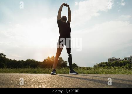 Young fit man with prosthetic leg doing stretching day routine outdoor - Disability and sport concept Stock Photo