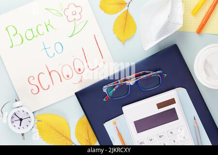 Back to school concept. School supplies on a tablet with glasses on a light background with yellow, autumn leaves, alarm clock and inscription Back to Stock Photo