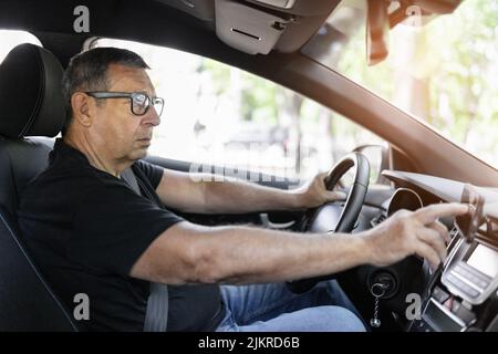 Senior behind the steering wheel using navigation and looking for directions Stock Photo