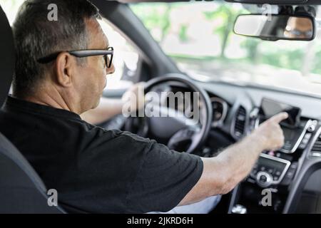 Senior behind the steering wheel using navigation and looking for directions Stock Photo