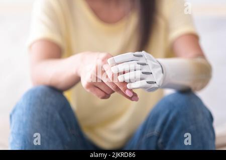 Close up two hands of woman with bionic arm, person lost her arm, girl artificial prosthetic limb, people with special needs . Stock Photo