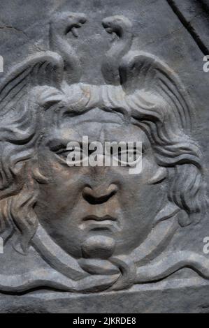 Gorgon or Medusa mask carved in triangular pediment on a finely sculpted Roman marble sarcophagus or tomb chest lid in the Necropolis of Manastirine, outside the walls of ancient Salona, capital of the Roman province of Dalmatia. The excavated archaeological site of Salona is at Solin, near Split, in southern Croatia.  Salona, with a population of about 60,000, was once the capital of the Roman province of Dalmatia.  In Greco-Roman art, Gorgons and Medusas were portrayed as monstrous or horrific faces with writhing, venomous snakes for hair. Stock Photo