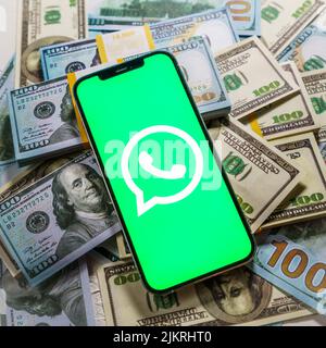 Berlin, Germany - February 02, 2022: Apple iPhone 12 Pro with messenger WhatsApp on the screen and dollar money Stock Photo