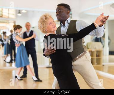 Elderly woman learning ballroom dancing in pair in dance studio Stock Photo