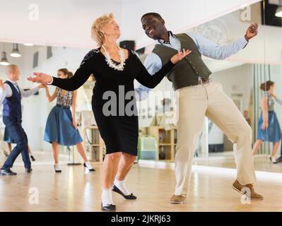 Lady learning to dance lindy hop with man in dance school Stock Photo
