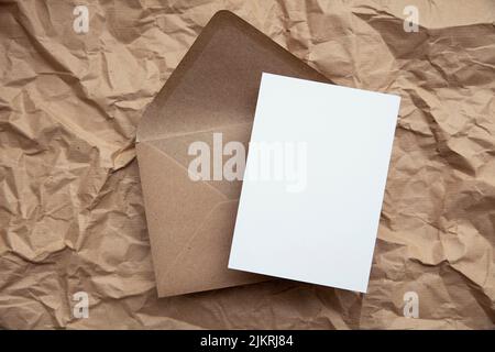 Blank card with kraft brown paper envelope template mock up on crumpled brown paper Stock Photo