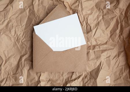 Blank card with kraft brown paper envelope template mock up on crumpled brown paper Stock Photo