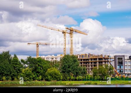 Minsk, Belarus - August 02, 2022: Tower cranes are working on the construction of residential buildings. View of cranes and construction site against Stock Photo