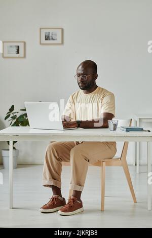 African young businessman sitting at his workplace at office and using laptop for online work Stock Photo