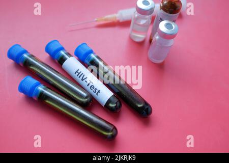 HIV blood test tubes and syringe on red background  Stock Photo