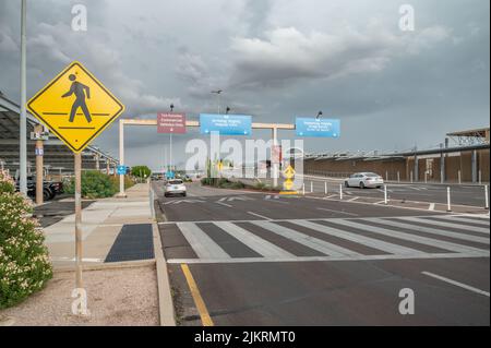 Vehicles arrive at Tucson International Airport next to parking lot. Directional signs display. Stock Photo