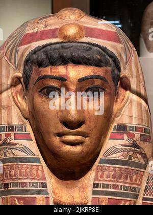 Mummy Mask of a Man, Stucco, gilded and painted, Roman Period, early 1st century C.E. Egypt:      Egyptian men living under Roman rule used mummy masks that combined contemporary and traditional elements. This example features locks of wavy black hair, a Roman fashion at this time. Stock Photo