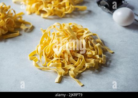 Fresh uncooked pasta nests on a gray background. Close up. Stock Photo