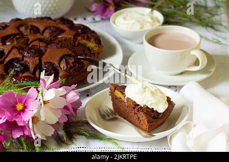 Chocolate plum cake with whipped cream, served with cocoa. Rustic style. Stock Photo