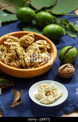 Young walnuts, shelled and in shell, walnut leaves. Rustic style. Stock Photo