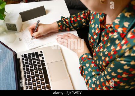 Defocus female hand writing pen. Unrecognizable elegant woman working on computer at office. Start or finish of a work day. Workspace. Top view. Time Stock Photo