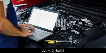 engine diagnostics - car mechanic using laptop computer to diagnose vehicle motor in repair shop. blank screen copy space Stock Photo
