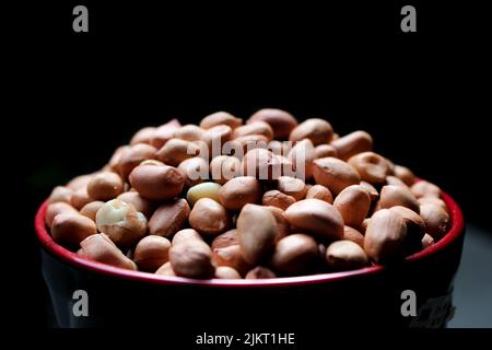 bunch of peeled peanuts or beans in a bowl with backbackground best for agricultural and food bacground. Stock Photo