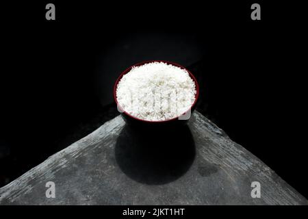 Uncooked dry rice in bowl on cement surface Stock Photo