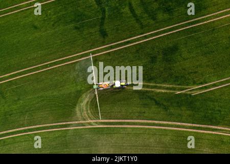 top down view of the tractor spraying the chemicals on the large green field, agriculture concept Stock Photo