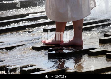 Berlin, Germany. 03rd Aug, 2022. A young woman cools off in a city fountain in the Mitte district in temperatures around 35 degrees Celsius. According to meteorologists, temperatures will continue to rise in the coming days. Credit: Wolfgang Kumm/dpa/Alamy Live News Stock Photo