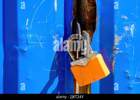 An old shabby padlock on a metal gate. Blue and orange colors Stock Photo