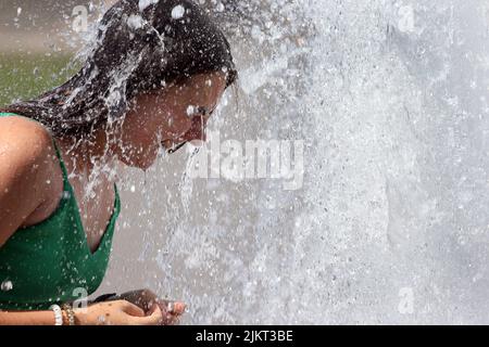 Berlin, Germany. 03rd Aug, 2022. A young Ukrainian woman enjoys the summer in the German capital and cools off at temperatures around 35 degrees Celsius in a city fountain in the Mitte district. According to meteorologists, temperatures will continue to rise in the coming days. Credit: Wolfgang Kumm/dpa/Alamy Live News Stock Photo