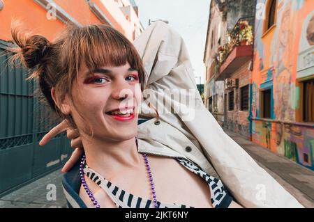 portrait of young transsexual latin caucasian woman standing on street happy posing with hand on head smiling looking at camera, horizontal image with Stock Photo
