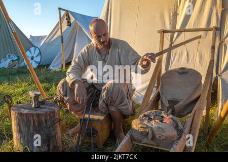 TVERSKAYA REGION, RUSSIA - JULY 23, 2022: A blacksmith-gunsmith inflates the forge of a camping forge. Historical camp of the festival 'Epic Coast - 2 Stock Photo