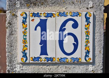 A closeup shot of the number sixteen sign tiles on a wall Stock Photo
