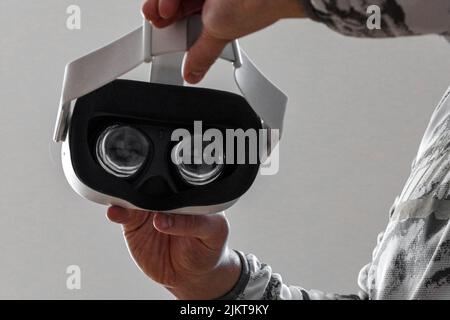 A man holding a virtual reality headset against a white wall background Stock Photo