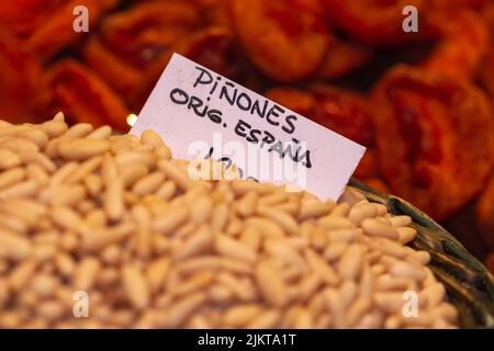 Bulk peeled pine nuts ready for sale, selective approach to the white sign, the sign translated into English means pine nuts of Spanish origin at the Stock Photo