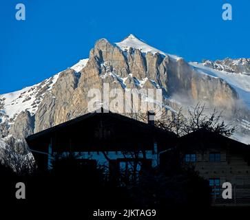 Swiss chalets beneath a snow-covered alpine peak, Ovronnaz, Valais, Switzerland Stock Photo