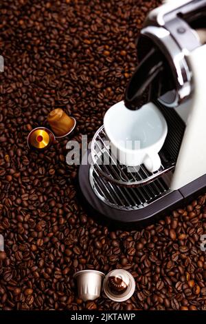 A vertical shot of a coffee making machine surrounded by coffee beans Stock Photo
