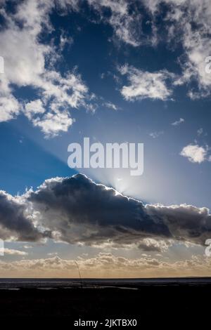 Sun beams behind clouds. Stock Photo